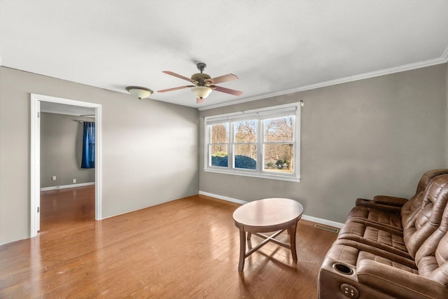 living room with ceiling fan, light wood-type flooring, and ornamental molding