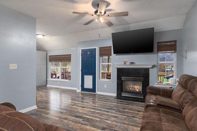 living room with ceiling fan, a fireplace, dark hardwood / wood-style flooring, and a textured ceiling