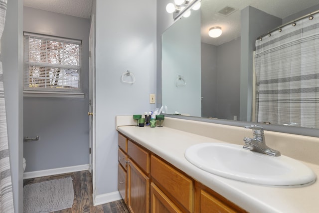 bathroom featuring toilet, a textured ceiling, vanity, curtained shower, and hardwood / wood-style flooring