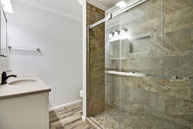 bathroom with crown molding, hardwood / wood-style floors, toilet, a shower with door, and vanity