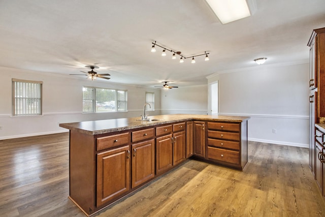 kitchen with hardwood / wood-style floors, an island with sink, crown molding, and sink