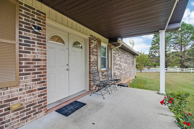 doorway to property featuring a lawn and covered porch