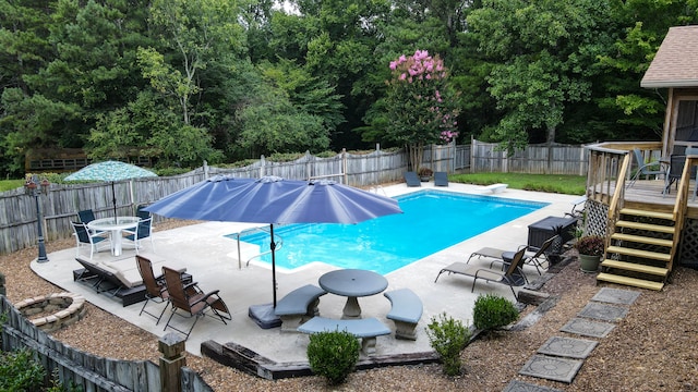 view of pool with a diving board, a fire pit, and a deck