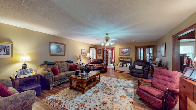 living room featuring hardwood / wood-style flooring, ceiling fan, a textured ceiling, and french doors