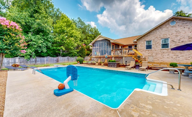 view of swimming pool with a wooden deck, a diving board, a patio area, and a sunroom