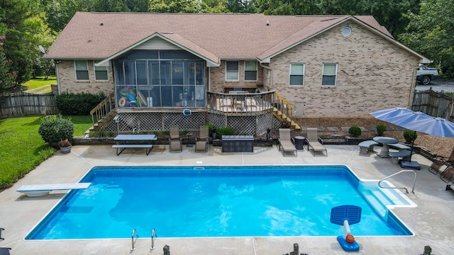 rear view of property featuring a pool side deck, a patio area, and a sunroom