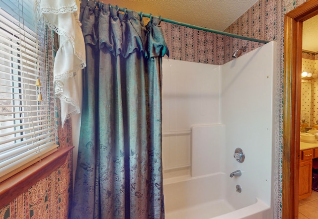 bathroom with tile patterned floors, sink, shower / bathtub combination with curtain, and a textured ceiling