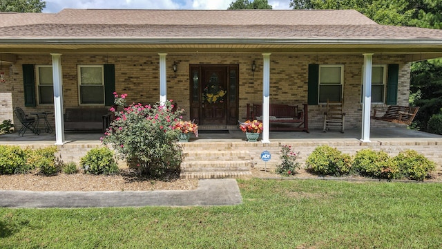 property entrance with covered porch and a yard