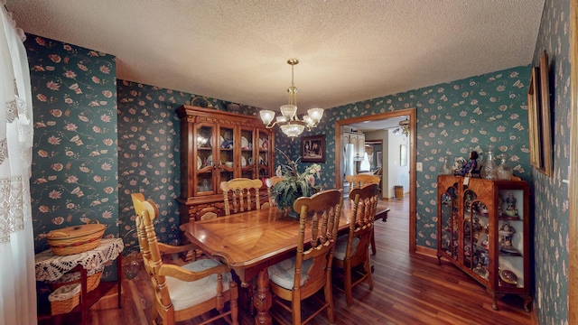 dining space featuring dark hardwood / wood-style floors, a textured ceiling, and a chandelier