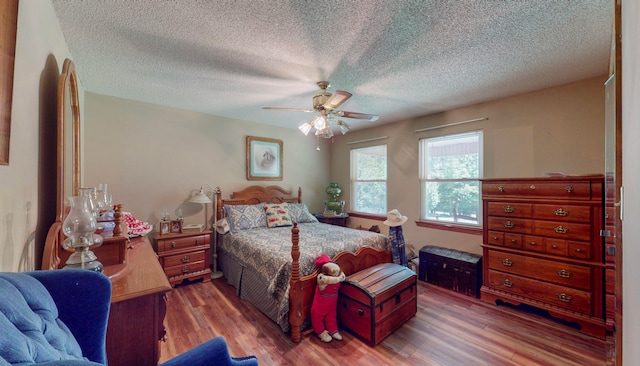 bedroom featuring hardwood / wood-style floors, a textured ceiling, and ceiling fan