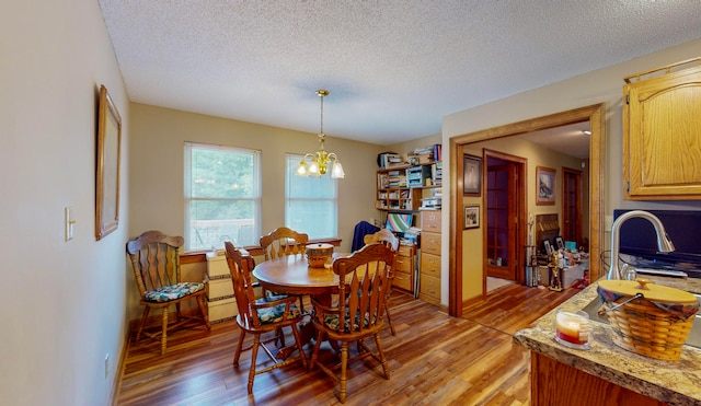 dining space featuring hardwood / wood-style floors, a textured ceiling, and an inviting chandelier