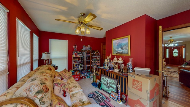 living room featuring ceiling fan, light hardwood / wood-style floors, and a textured ceiling