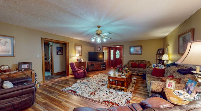 living room featuring hardwood / wood-style floors, ceiling fan, and a textured ceiling