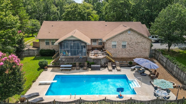 exterior space with a sunroom, a lawn, a diving board, a patio area, and a deck