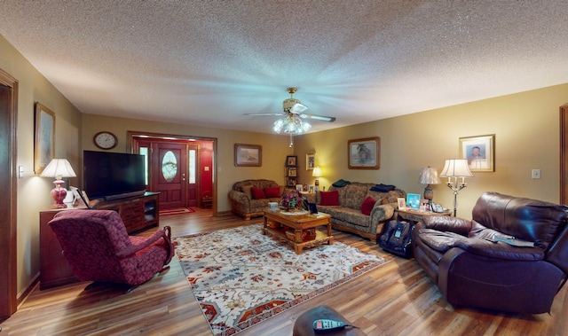 living room featuring hardwood / wood-style floors, ceiling fan, and a textured ceiling