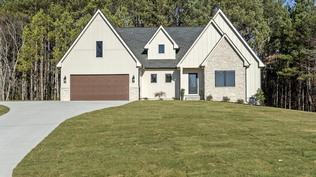 modern inspired farmhouse with board and batten siding, a shingled roof, concrete driveway, a front yard, and an attached garage