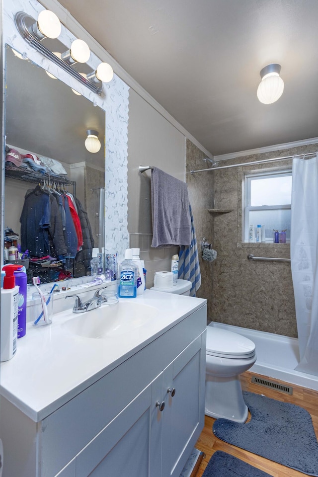 bathroom featuring vanity, hardwood / wood-style flooring, toilet, ornamental molding, and walk in shower