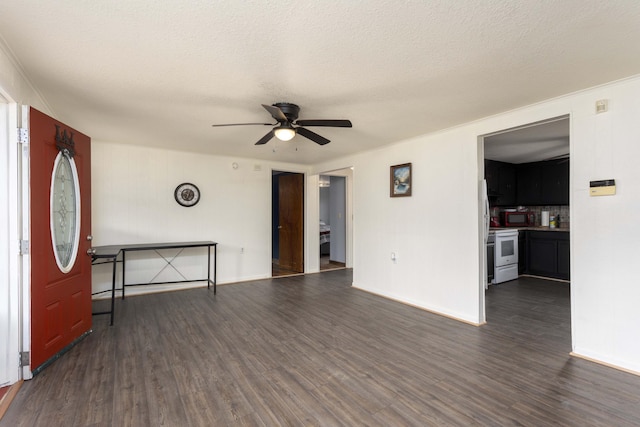 unfurnished living room featuring a textured ceiling, ceiling fan, and dark wood-type flooring