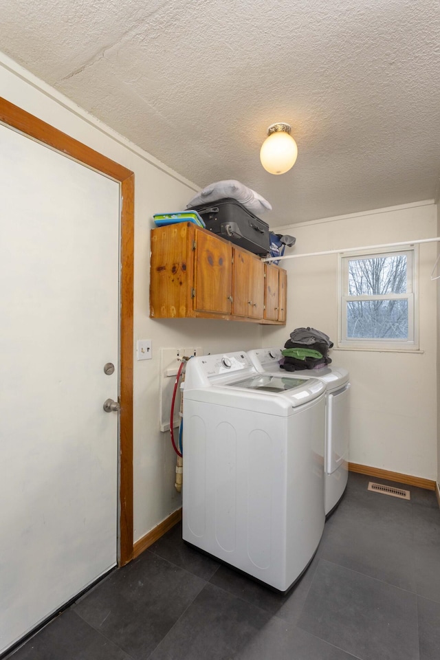 laundry room with cabinets, a textured ceiling, and washer and dryer