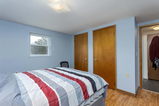 bedroom with light hardwood / wood-style floors and two closets