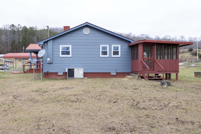 back of house with a carport, a yard, cooling unit, and a sunroom