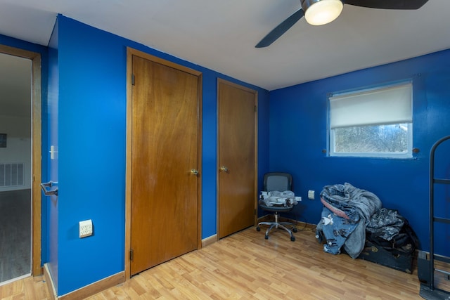 interior space featuring ceiling fan, light wood-type flooring, and two closets