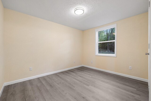 spare room featuring light hardwood / wood-style floors and a textured ceiling