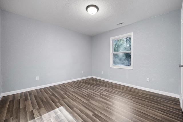 empty room with dark wood-type flooring and a textured ceiling