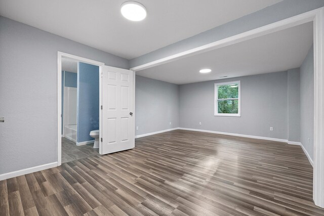 unfurnished bedroom featuring dark hardwood / wood-style flooring and ensuite bath