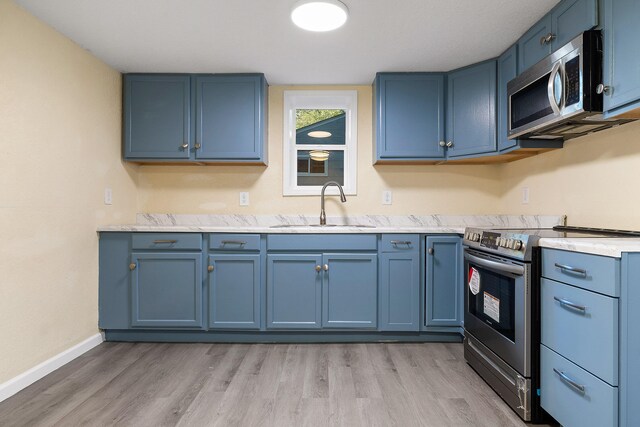 kitchen featuring light hardwood / wood-style floors, sink, blue cabinets, and stainless steel appliances