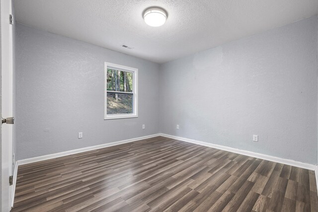 unfurnished room with a textured ceiling and dark hardwood / wood-style floors