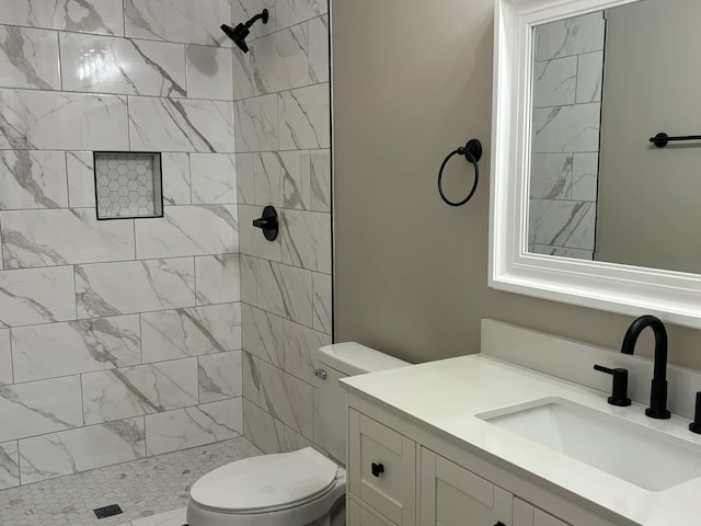 bathroom with vanity, tiled shower, and toilet