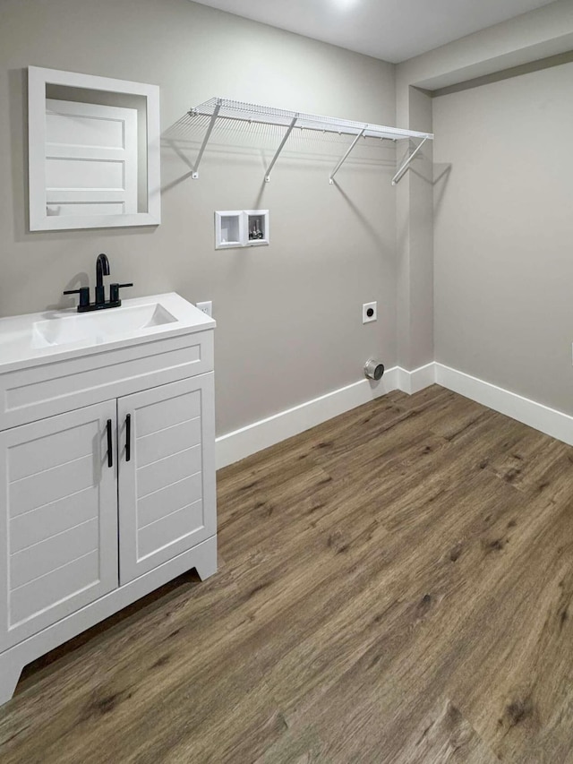 washroom with hookup for an electric dryer, sink, washer hookup, and dark wood-type flooring