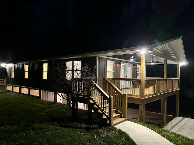 view of front of property with a deck, ceiling fan, and a lawn