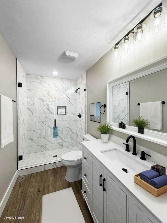 bathroom with vanity, wood-type flooring, toilet, and a tile shower