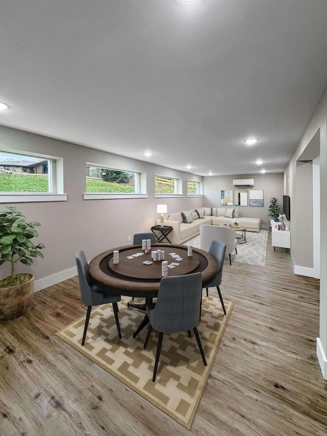 dining space featuring a healthy amount of sunlight, a wall mounted AC, and light hardwood / wood-style flooring