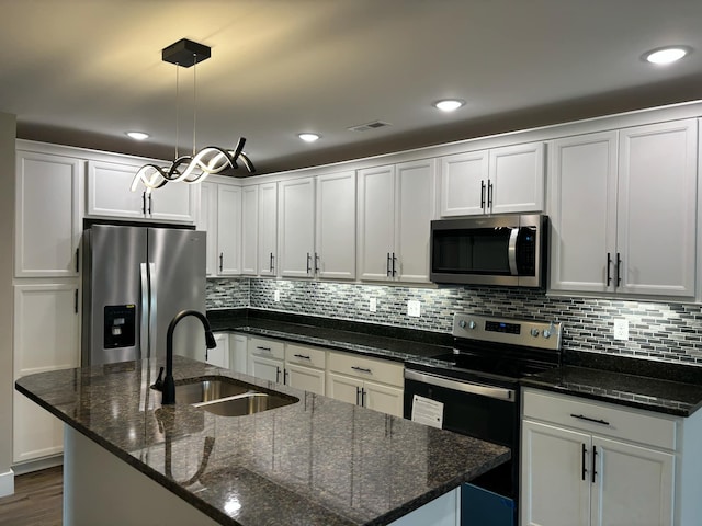 kitchen with an island with sink, appliances with stainless steel finishes, decorative light fixtures, and sink