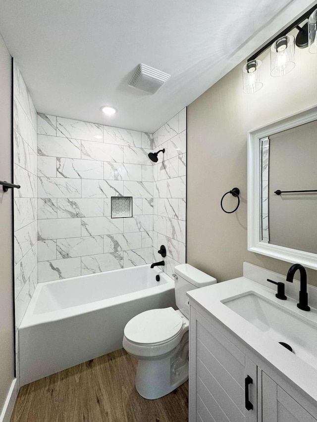 full bathroom featuring vanity, tiled shower / bath combo, wood-type flooring, and toilet