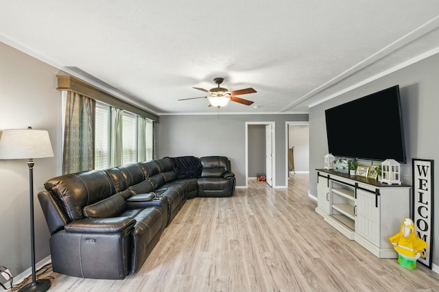 living area featuring ornamental molding, ceiling fan, light wood-style floors, and baseboards