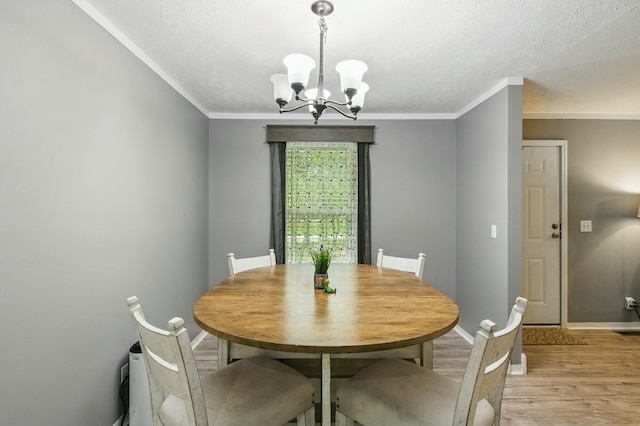 dining area featuring a notable chandelier, baseboards, crown molding, and light wood-style flooring