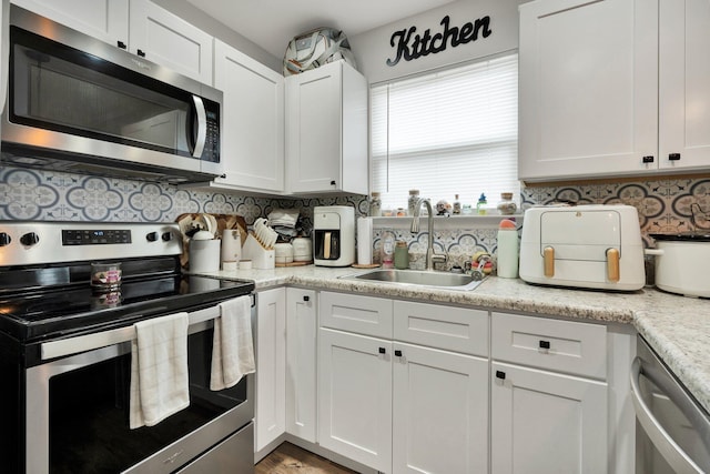 1042 Mccann Dr SE, Cleveland, TN 37311 - kitchen with backsplash, a sink, stainless steel appliances, and white cabinetry