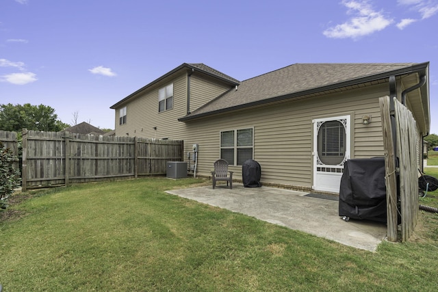 rear view of property featuring a yard, a patio, and central AC