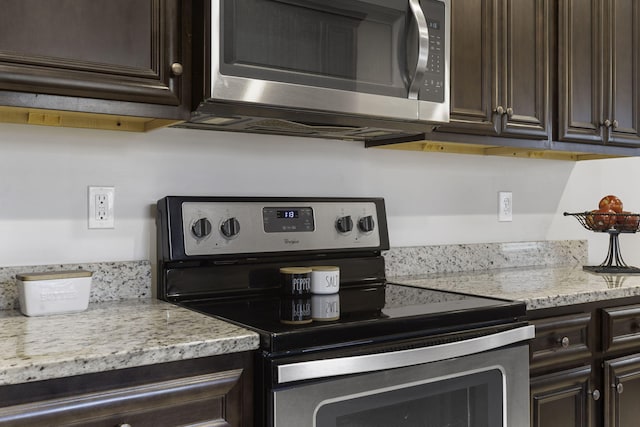 kitchen featuring dark brown cabinetry, light stone counters, and stainless steel appliances