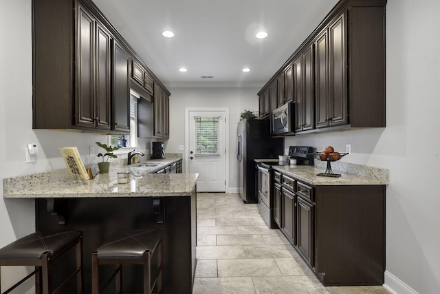 kitchen with sink, stainless steel appliances, light stone counters, kitchen peninsula, and a breakfast bar area