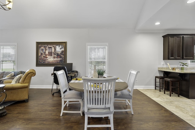 dining room featuring a notable chandelier, dark wood-type flooring, and vaulted ceiling