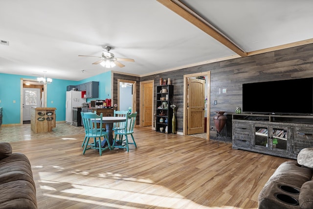 living room featuring beam ceiling, wooden walls, light hardwood / wood-style flooring, and ceiling fan with notable chandelier