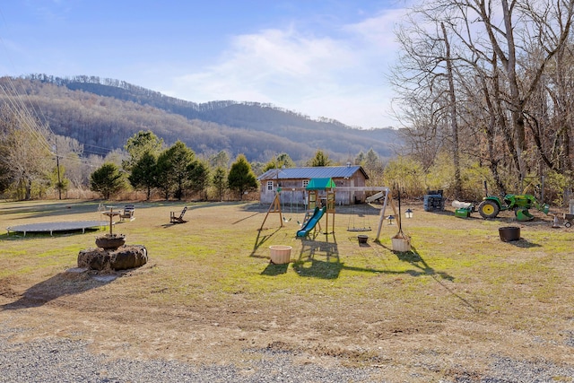 view of playground featuring a lawn and a mountain view