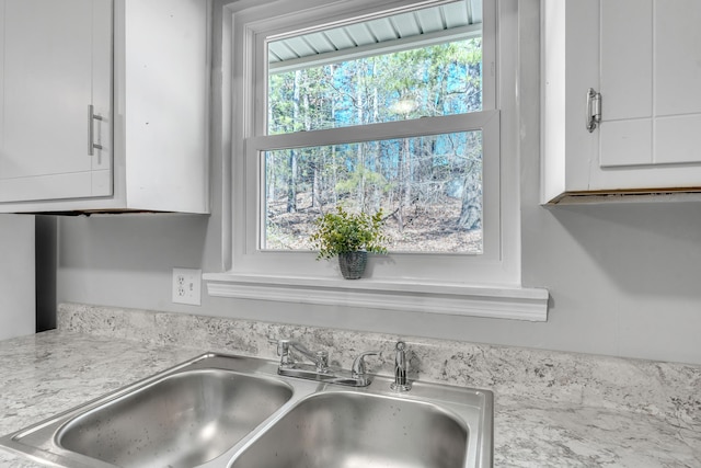 details with white cabinets, a sink, and light countertops