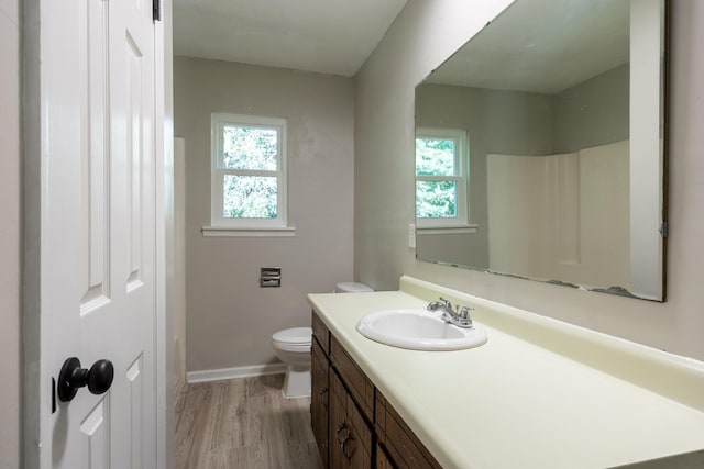 bathroom with a healthy amount of sunlight, vanity, toilet, and wood finished floors