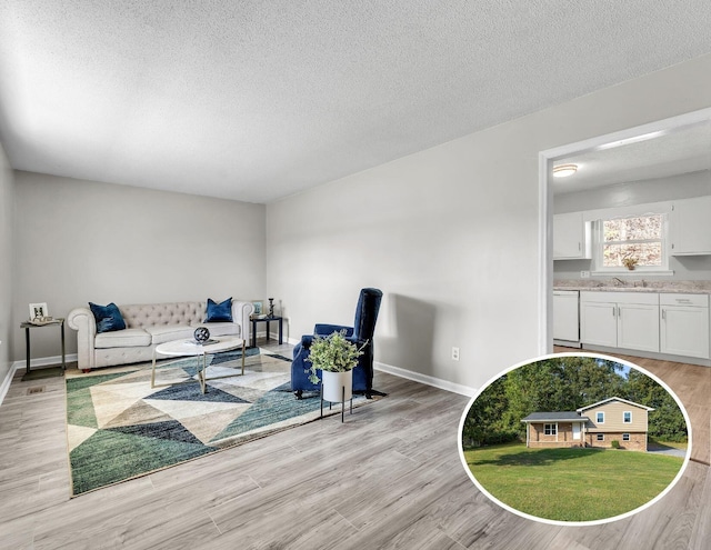 living area featuring light wood-style floors, baseboards, and a textured ceiling